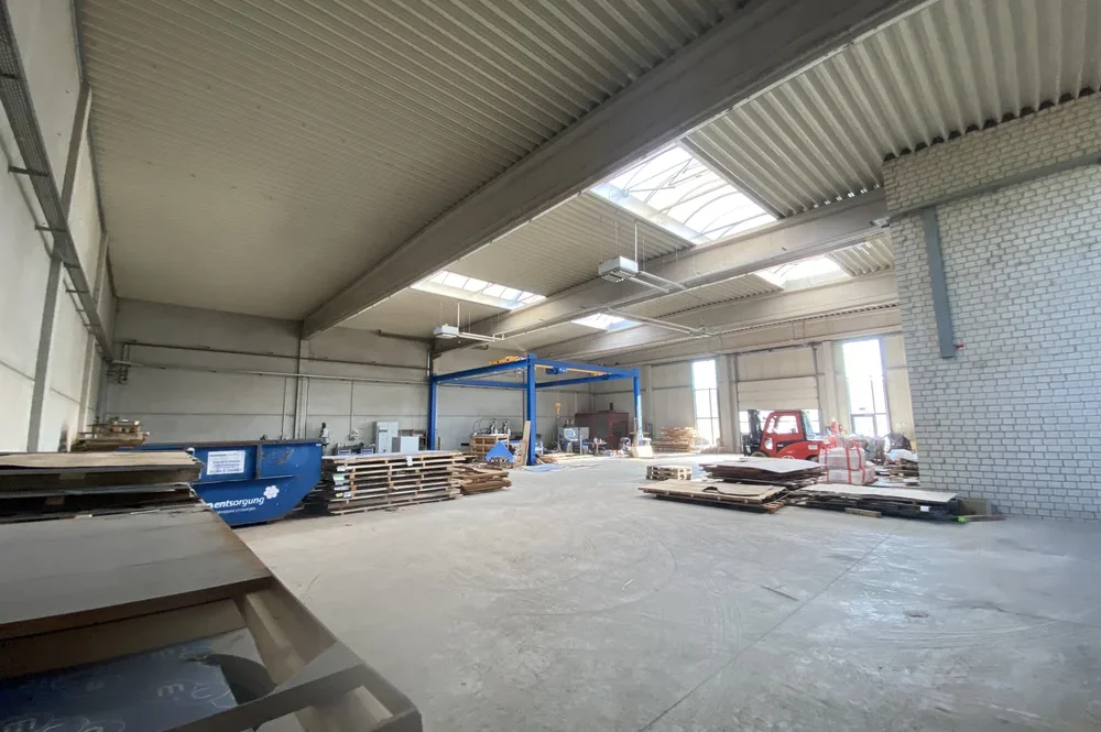 Innenansicht der Gewerbehalle aus der hinteren Ecke mit Blick auf die Hallenfläche und das Zugangstor
