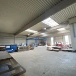 Innenansicht der Gewerbehalle aus der hinteren Ecke mit Blick auf die Hallenfläche und das Zugangstor